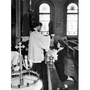  Priest sprinkling Holy Water on baby held by woman in 